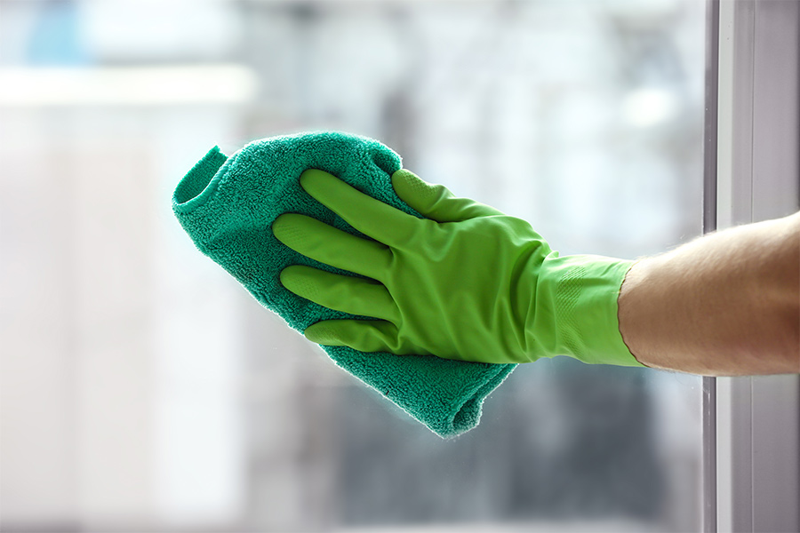 hand with green glove and towel cleaning window clayton nc